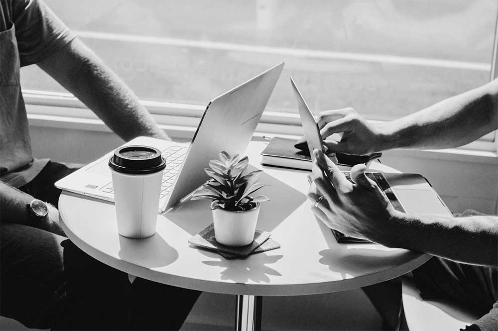 Two people working at a table with laptops open.